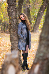 Image showing A young beautiful girl leaned back against the tree in the forest