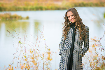 Image showing Portrait of a young girl on the background of a lake in autumn weather