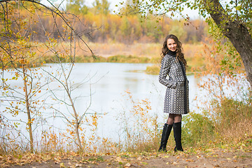 Image showing A young girl walks by the river in the autumn forest