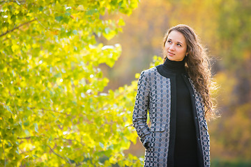 Image showing Cute young girl looking to the left on the background of autumn yellow foliage