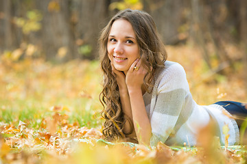 Image showing Young beautiful girl lies on the weave at a picnic in the autumn forest