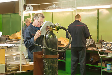 Image showing Elderly mechanic reads drawing in shop