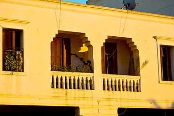 Image showing   yellow window in and brown wall  