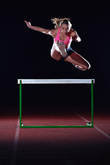 Image showing woman athlete jumping over a hurdles