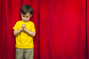 Image showing Mixed Race Boy Praying in Front of Red Curtain