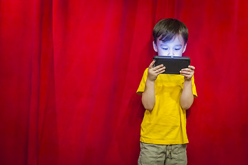Image showing Mixed Race Boy Watching Cell Phone in Front of Curtain