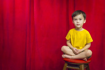 Image showing Mixed Race Boy Sitting on Stool in Front of Curtain