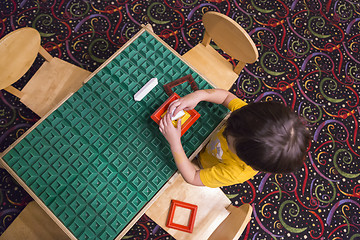 Image showing Overhead of Boy Playing With His Toys at Table