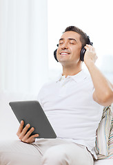 Image showing smiling man with tablet pc and headphones at home