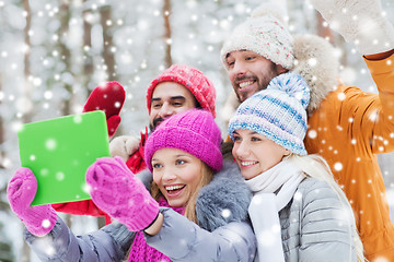 Image showing smiling friends with tablet pc in winter forest