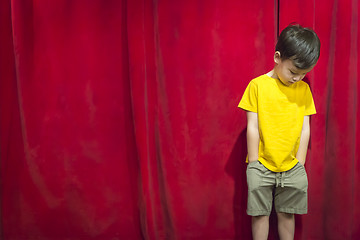 Image showing Pouting Mixed Race Boy Standing In Front of Red Curtain