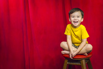 Image showing Laughing Boy Sitting on Stool in Front of Curtain