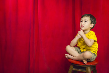 Image showing Mixed Race Boy Sitting on Stool in Front of Curtain