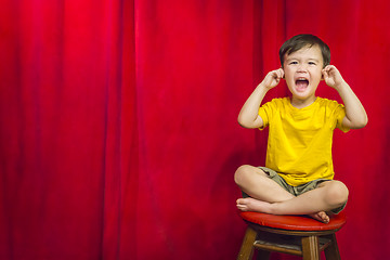 Image showing Boy, Fingers In Ears on Stool in Front of Curtain