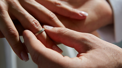 Image showing groom puts ring on the finger of bride