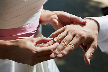 Image showing bride puts ring on finger of groom