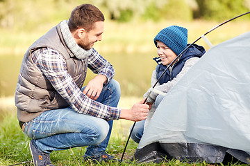 Image showing happy father and son setting up tent outdoors