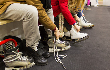 Image showing close up of friends wearing skates on skating rink