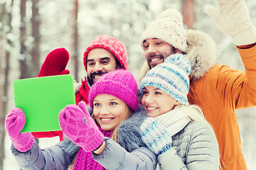 Image showing smiling friends with tablet pc in winter forest