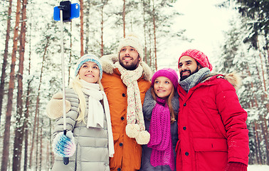 Image showing smiling friends with smartphone in winter forest
