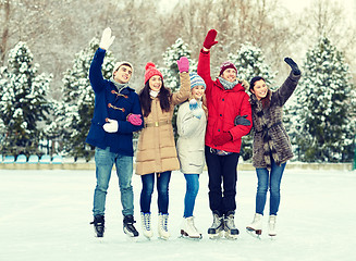 Image showing happy friends ice skating on rink outdoors