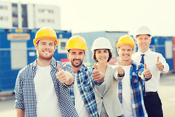 Image showing group of smiling builders in hardhats outdoors