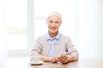 Image showing senior woman with smartphone texting at home