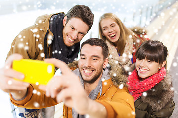 Image showing happy friends with smartphone on skating rink