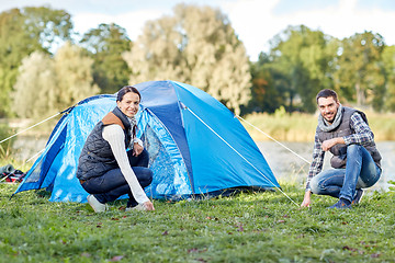 Image showing happy couple setting up tent outdoors
