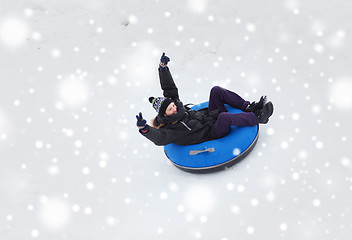 Image showing happy young man sliding down on snow tube