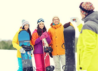 Image showing happy friends with snowboards and smartphone