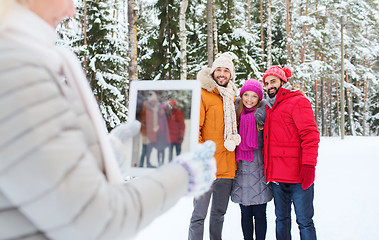 Image showing smiling friends with tablet pc in winter forest