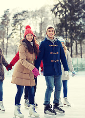 Image showing happy friends ice skating on rink outdoors