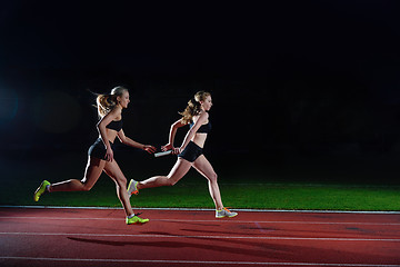 Image showing athletic runners passing baton in relay race