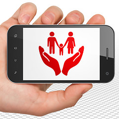 Image showing Insurance concept: Hand Holding Smartphone with Family And Palm on display