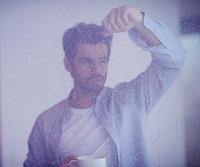 Image showing relaxed young man drink first morning coffee withh rain drops on