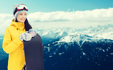 Image showing happy young woman with snowboard over mountains