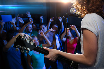 Image showing female singer playing guitar over happy fans crowd