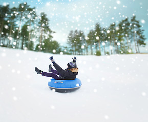 Image showing happy young man sliding down on snow tube