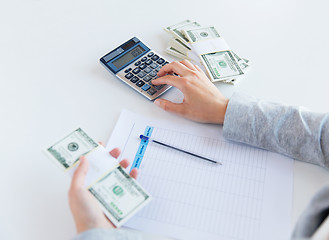 Image showing close up of hands counting money with calculator