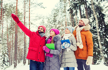 Image showing smiling friends with tablet pc in winter forest