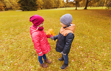 Image showing little boy giving autumn maple leaves to girl