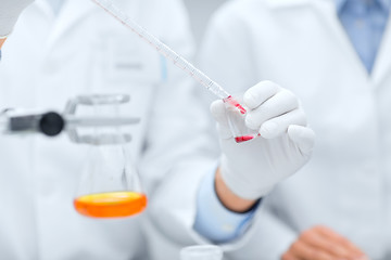 Image showing close up of scientists filling test tube in lab