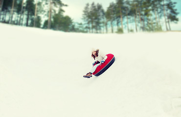 Image showing happy teenage girl sliding down on snow tube