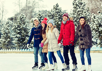 Image showing happy friends ice skating on rink outdoors