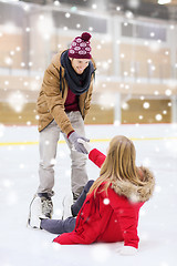 Image showing man helping women to rise up on skating rink