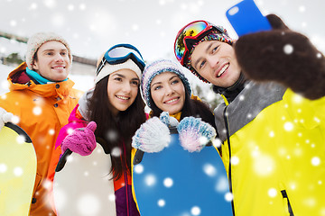 Image showing happy friends with snowboards and smartphone