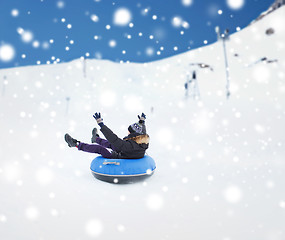 Image showing happy young man sliding down on snow tube