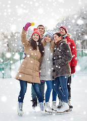 Image showing happy friends with smartphone on ice skating rink