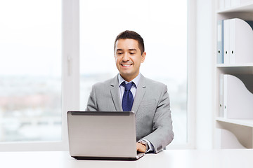 Image showing happy businessman working with laptop in office